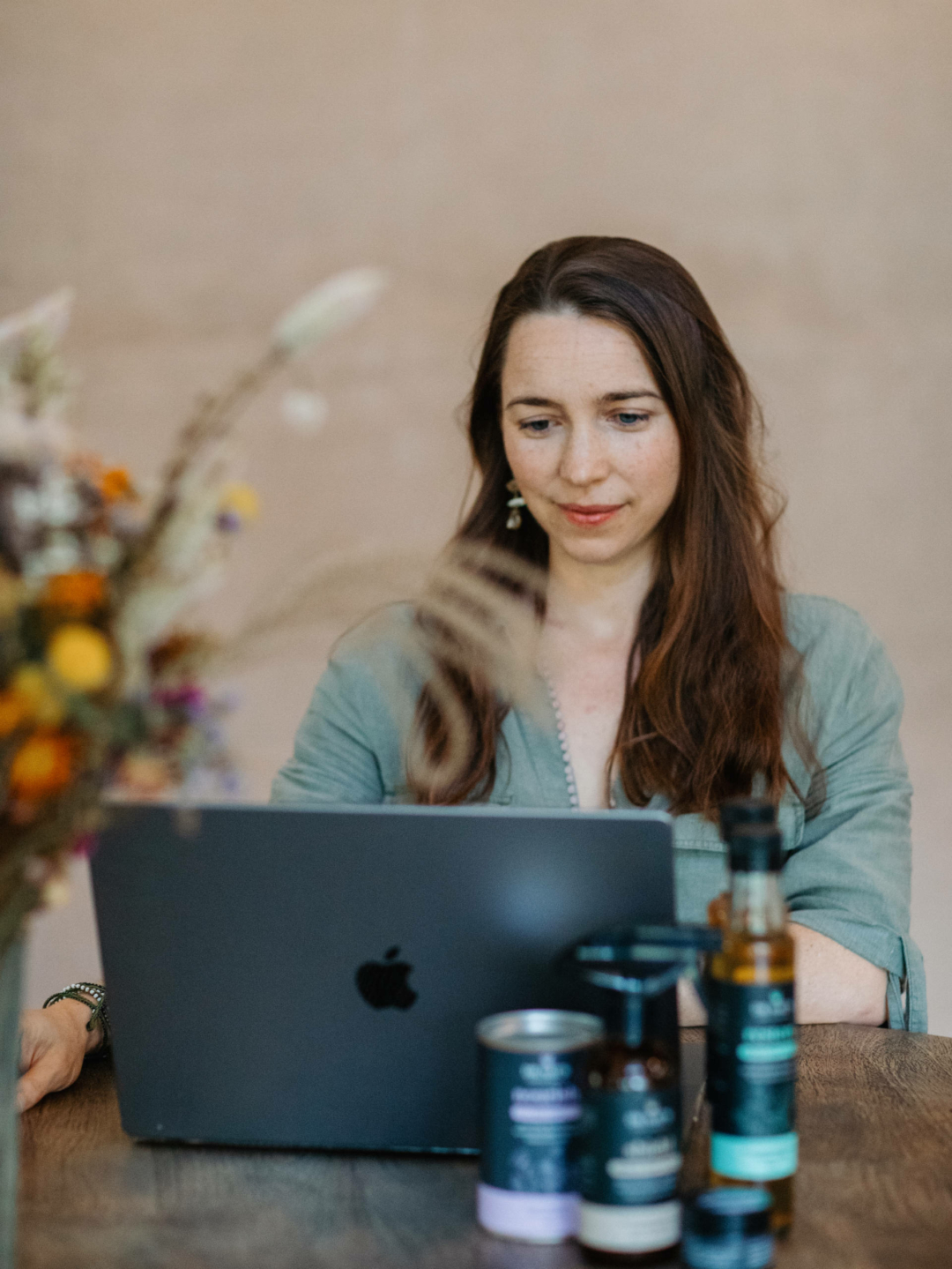 Dr Nat sits in front of a laptop, conducting a consultation, Ar Nats products are seen in the foreground.