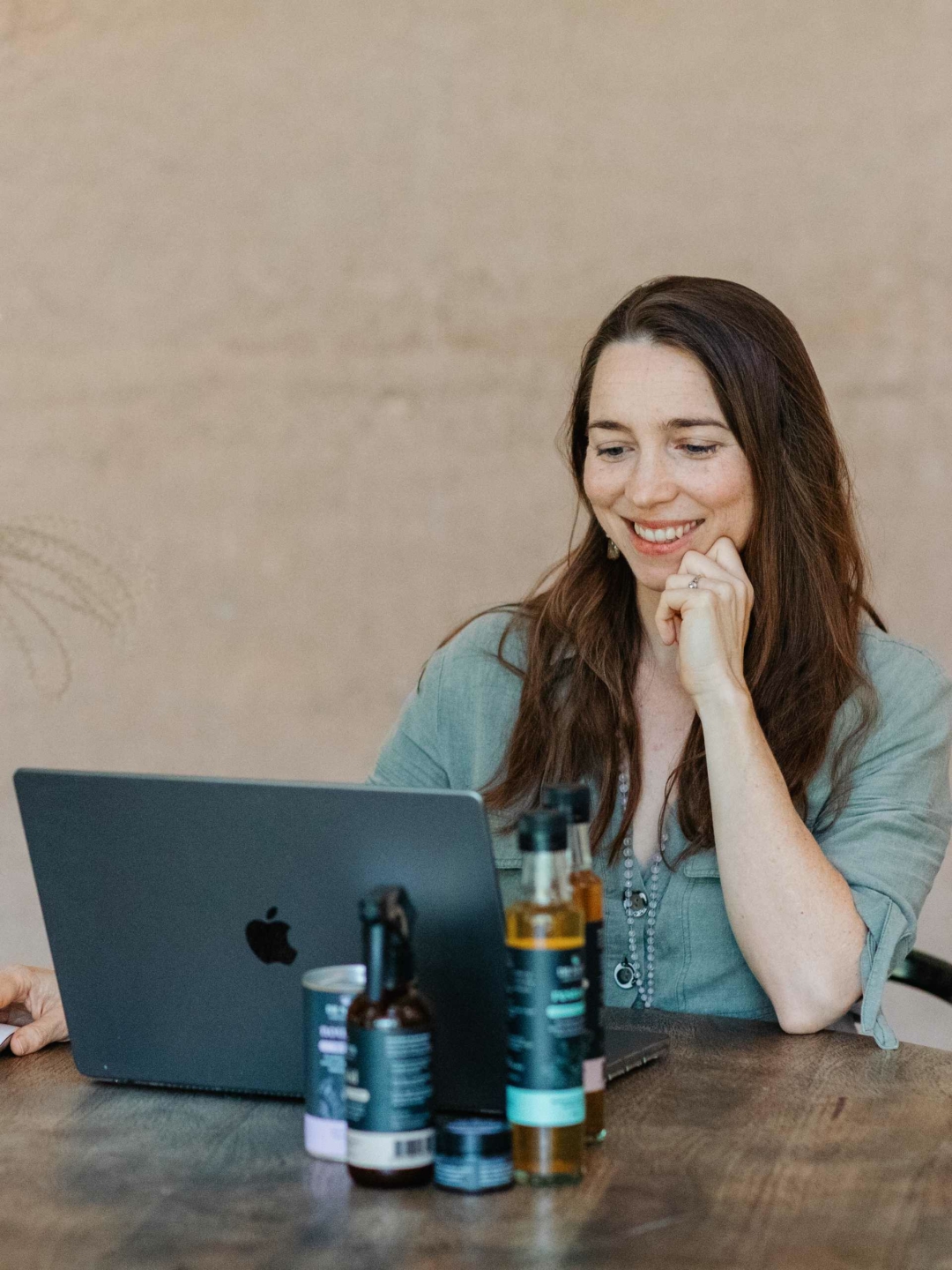 Dr Nat sits in front of a laptop, conducting a consultation, Ar Nats products are seen in the foreground.